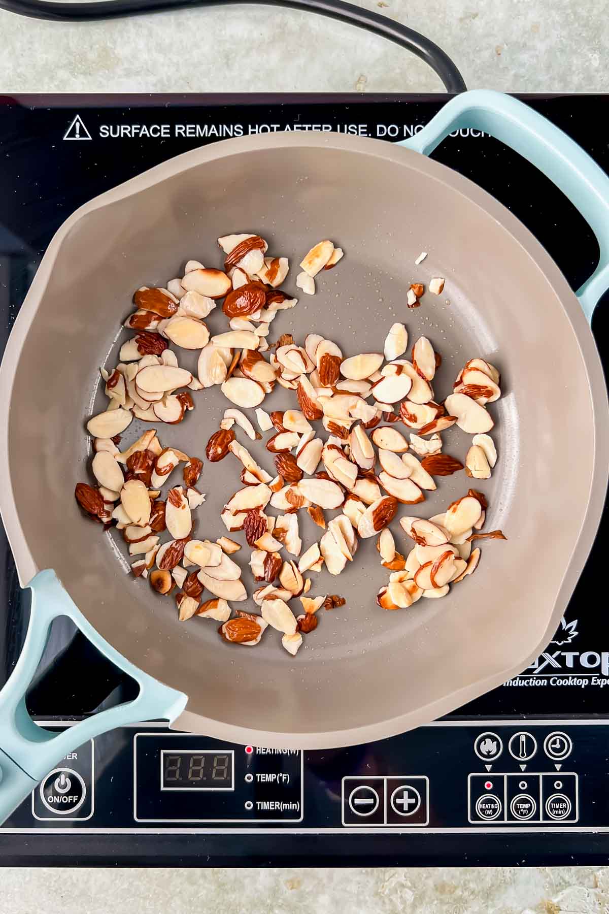 small skillet with toasted shaved almonds on hot plate. 