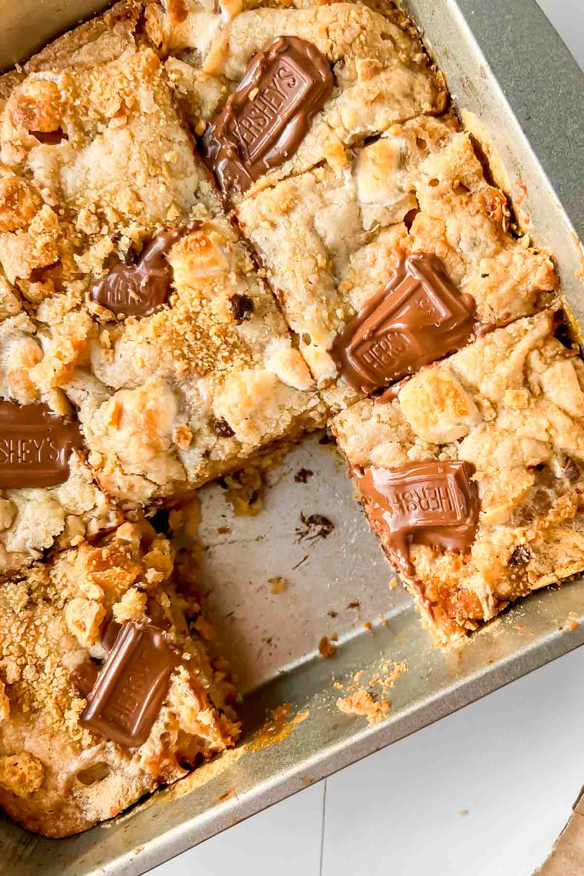 Smores casserole in square pan with hersheys squares on top cut into squares.