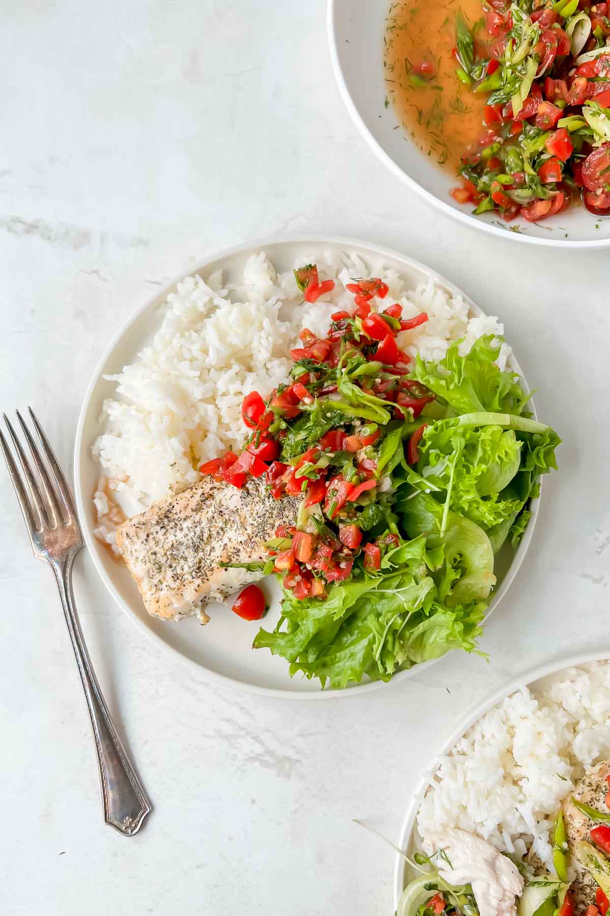 serving plate filled with rice, mahi mahi and greens with tomato relish on top.