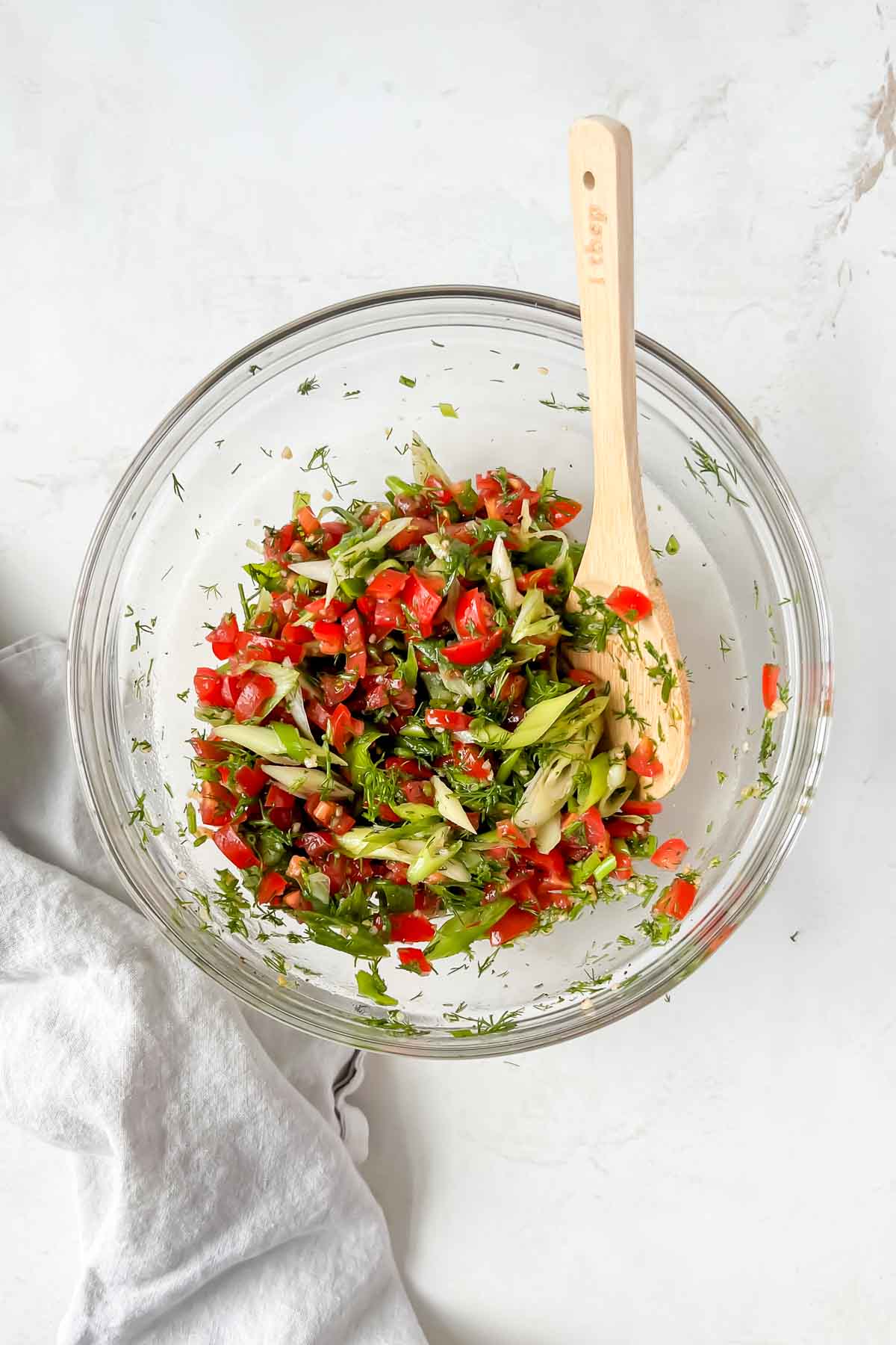 tomato relish ingredients tossed in clear glass mixing bowl.
