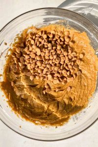 pumpkin muffin batter with butterscotch chips in glass mixing bowl.
