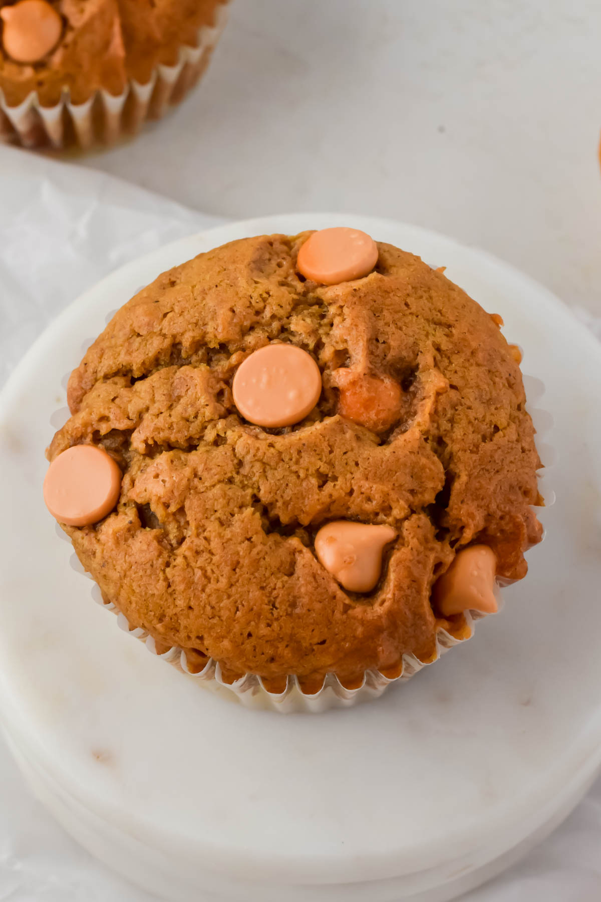 macro image of one butterscotch pumpkin muffin on white marble slab.