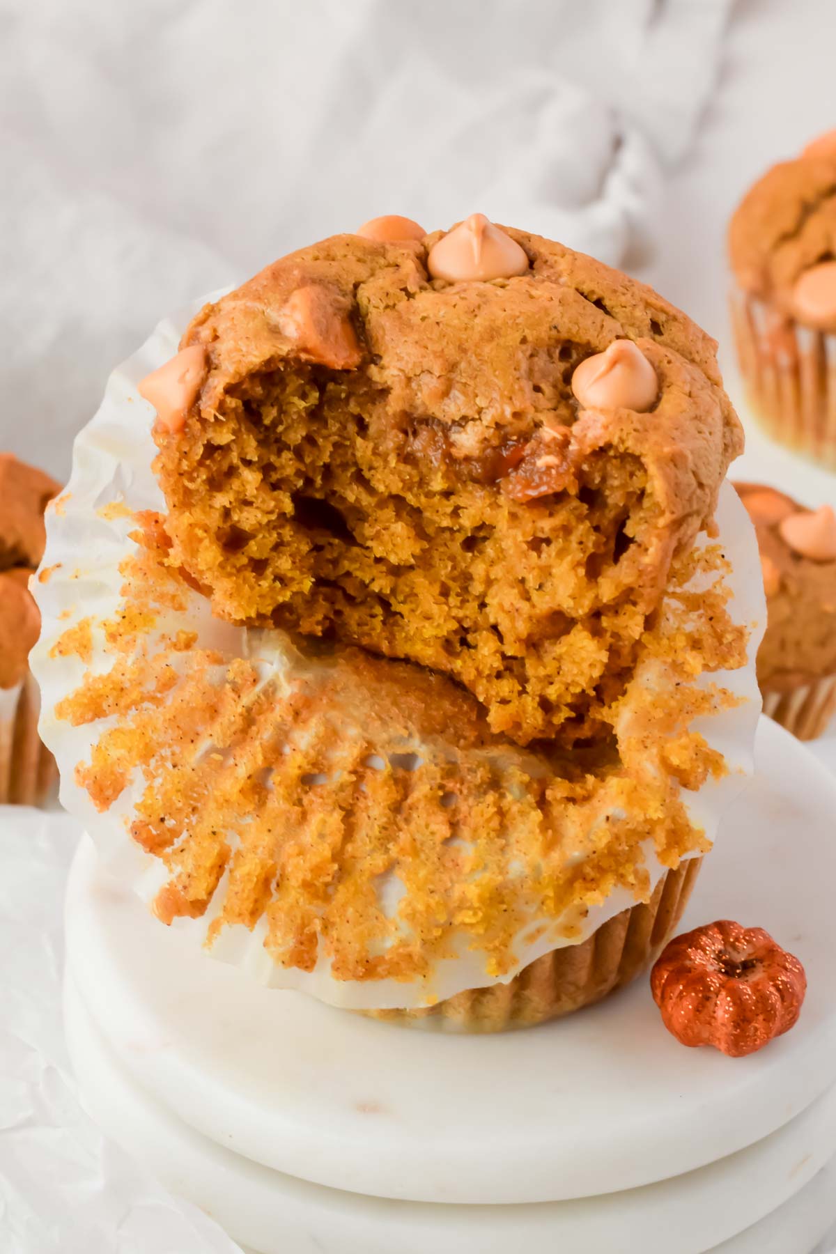 bite out of one butterscotch pumpkin muffin on top of white marble slab.