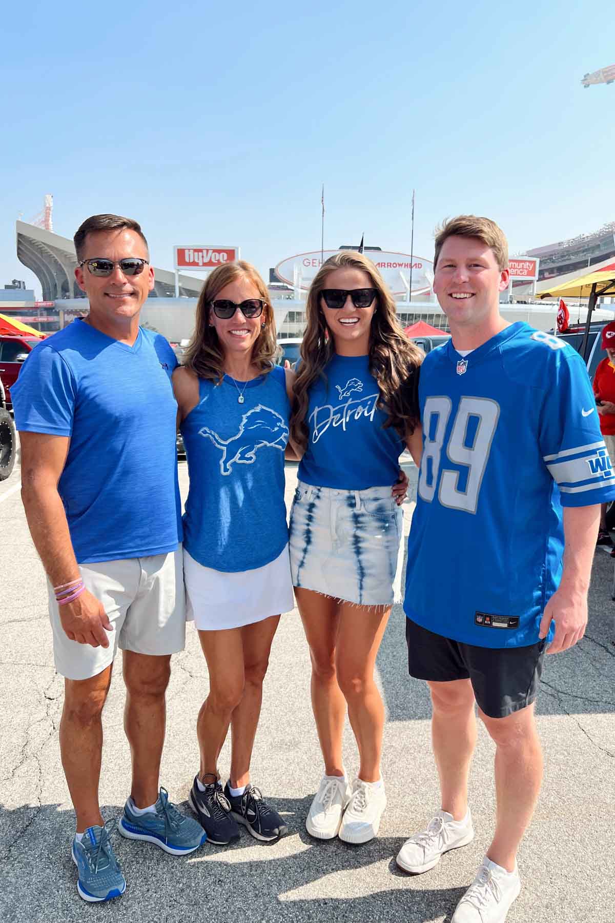 two women and two men in Detroit Lions gear standing in front of Kansas City Arrowhead stadium. 