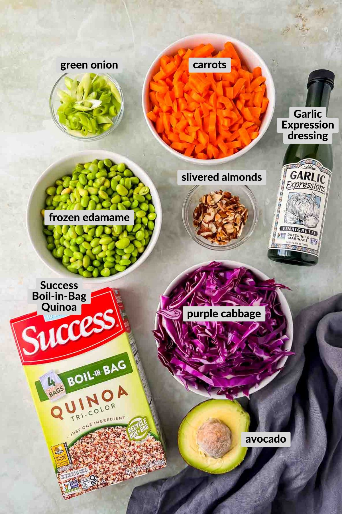 ingredients for quinoa edamame salad in individuals bowls on grey background.