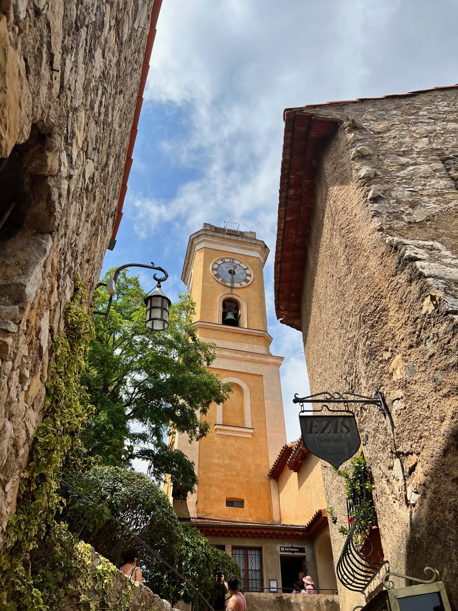 charming city of Eze clock town and cloudy blue sky.