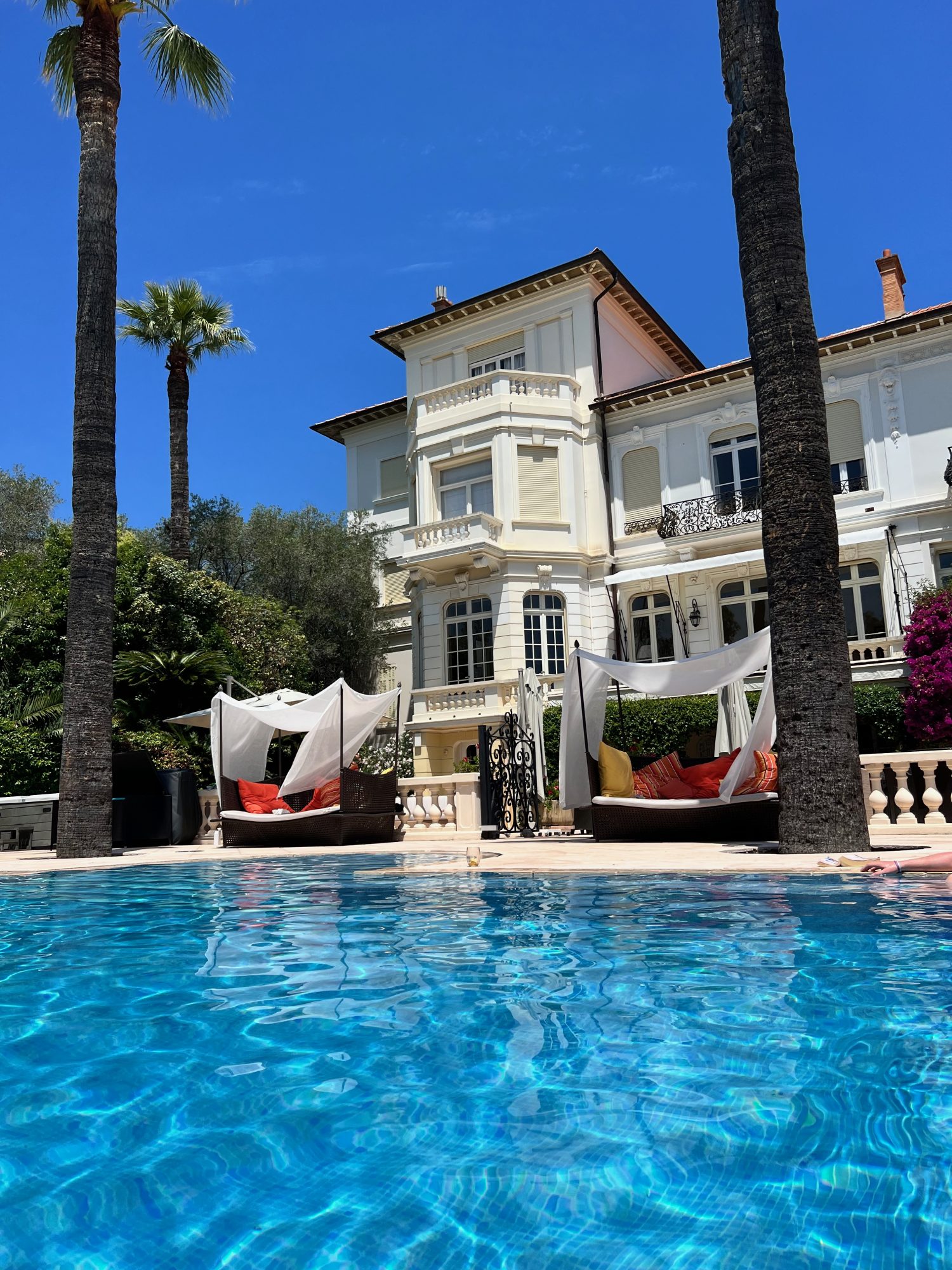 private pool overlooking a three story white villa in the French Riviera.