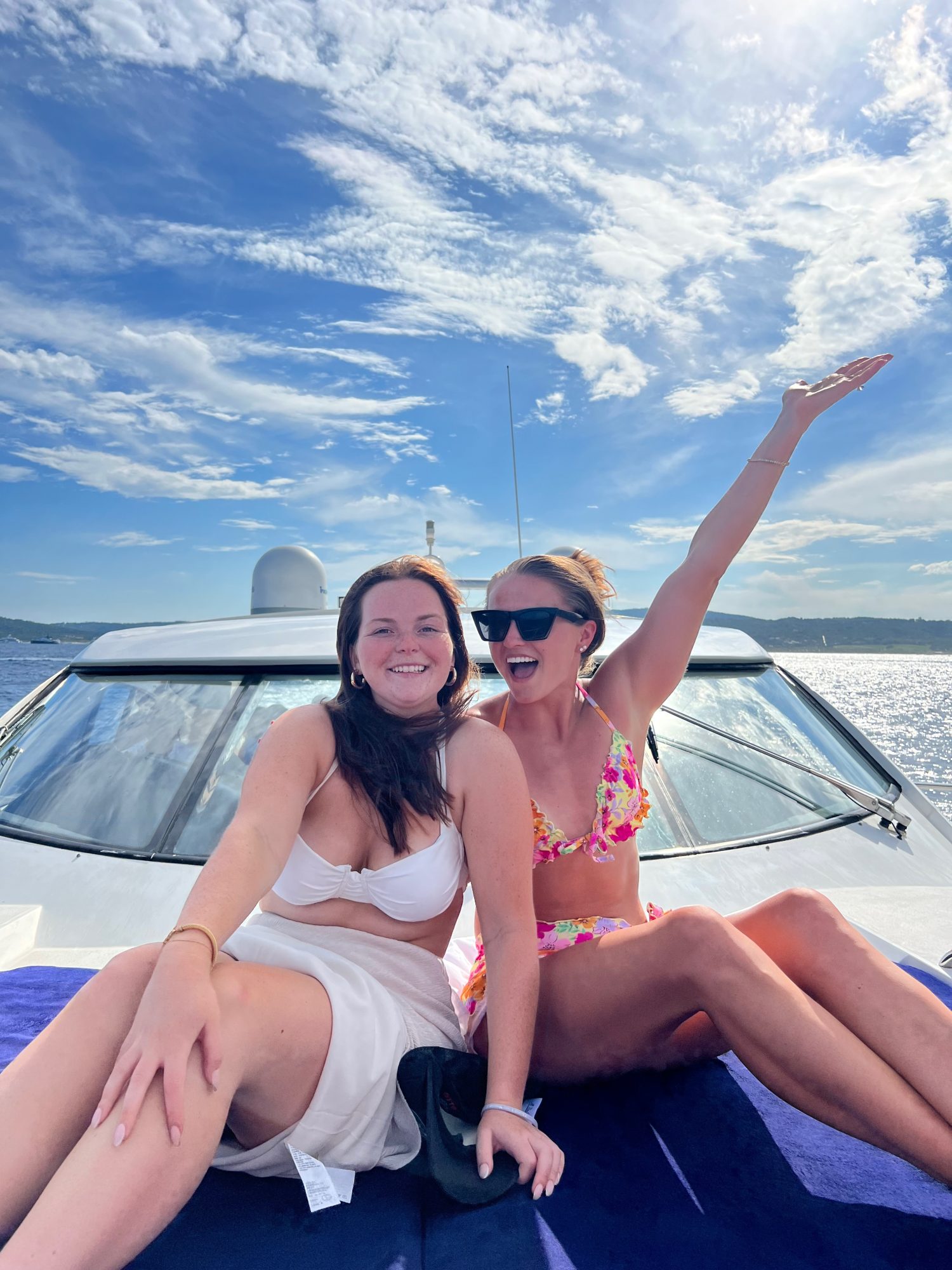 two girls in bathing suits on the top of a yacht. 