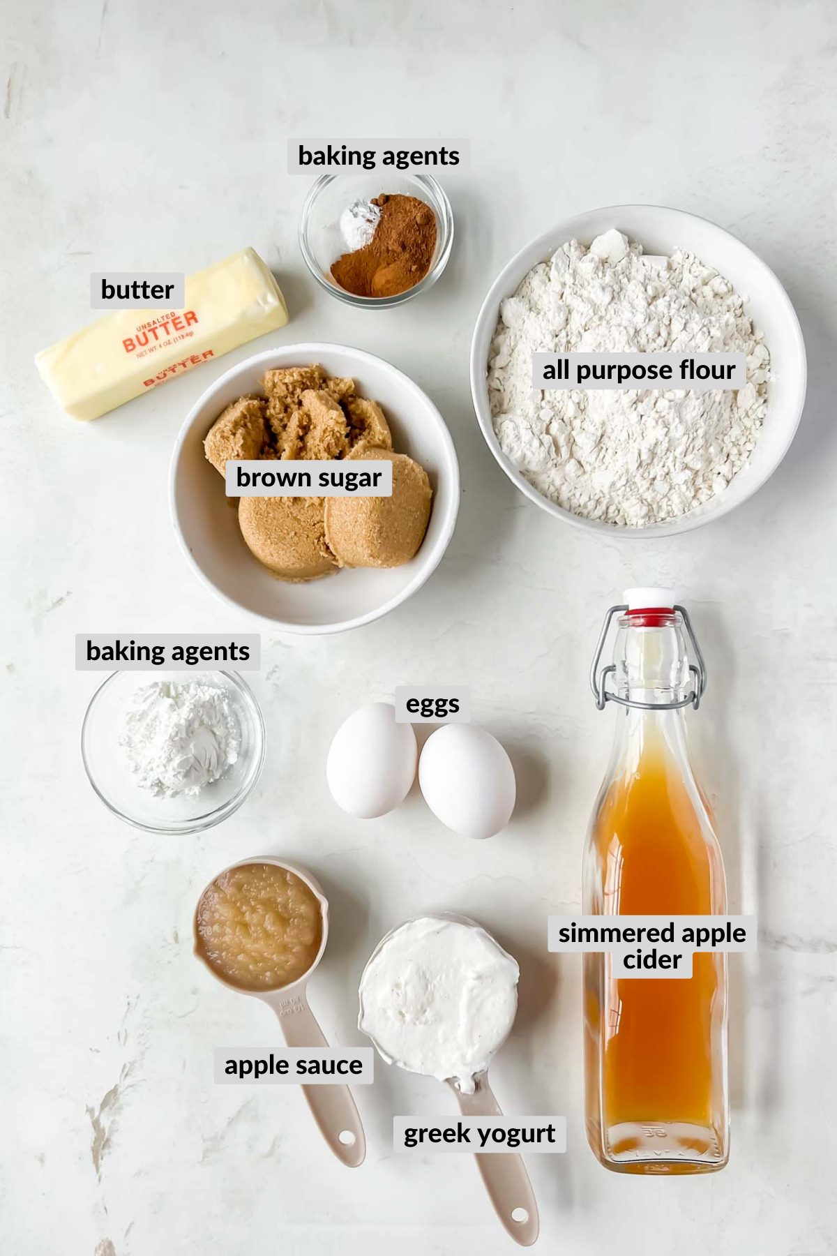 ingredients for cinnamon donut bread in individual bowls on white background.