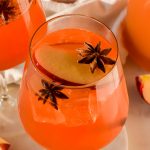 apple cider spritz in a wine glass garnished with apple slices and star anise.