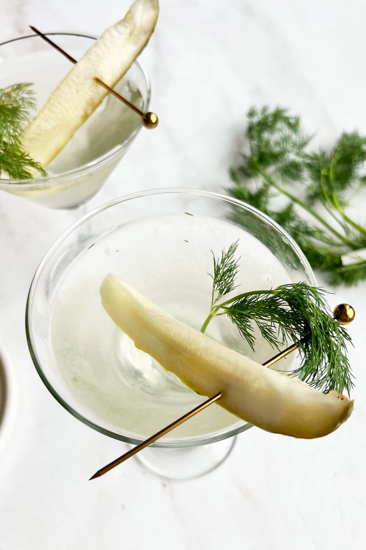 close overhead image of dill pickle martinis garnished with pickle spear and fresh dill.