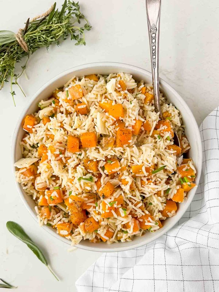 seasoned butternut squash herb rice pilaf mixed together in white serving bowl.