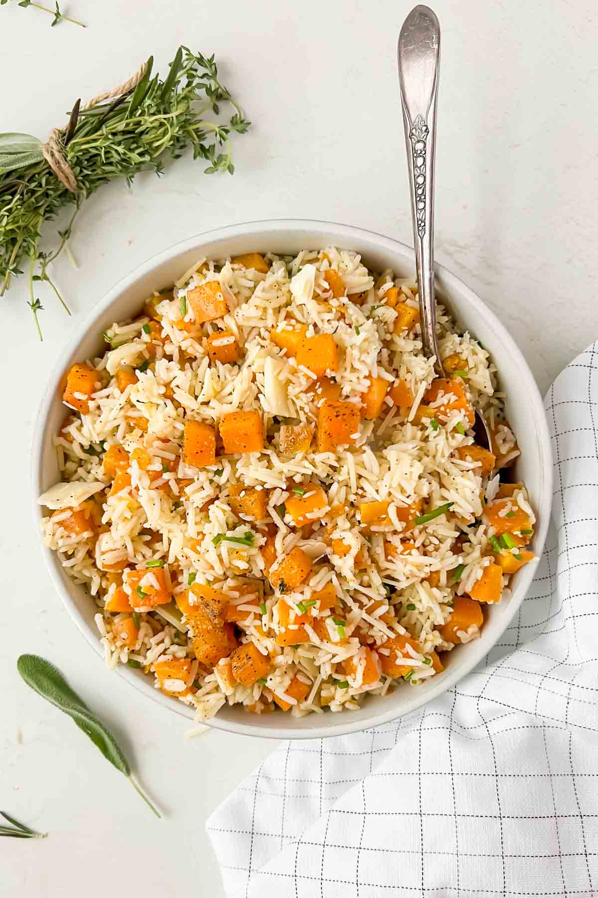 seasoned butternut squash herb rice pilaf mixed together in white serving bowl.