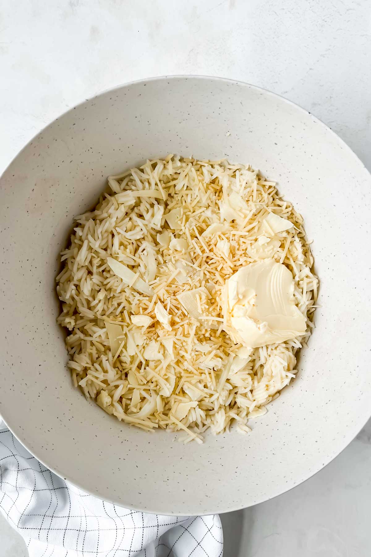rice, cheese, and butter in white mixing bowl.