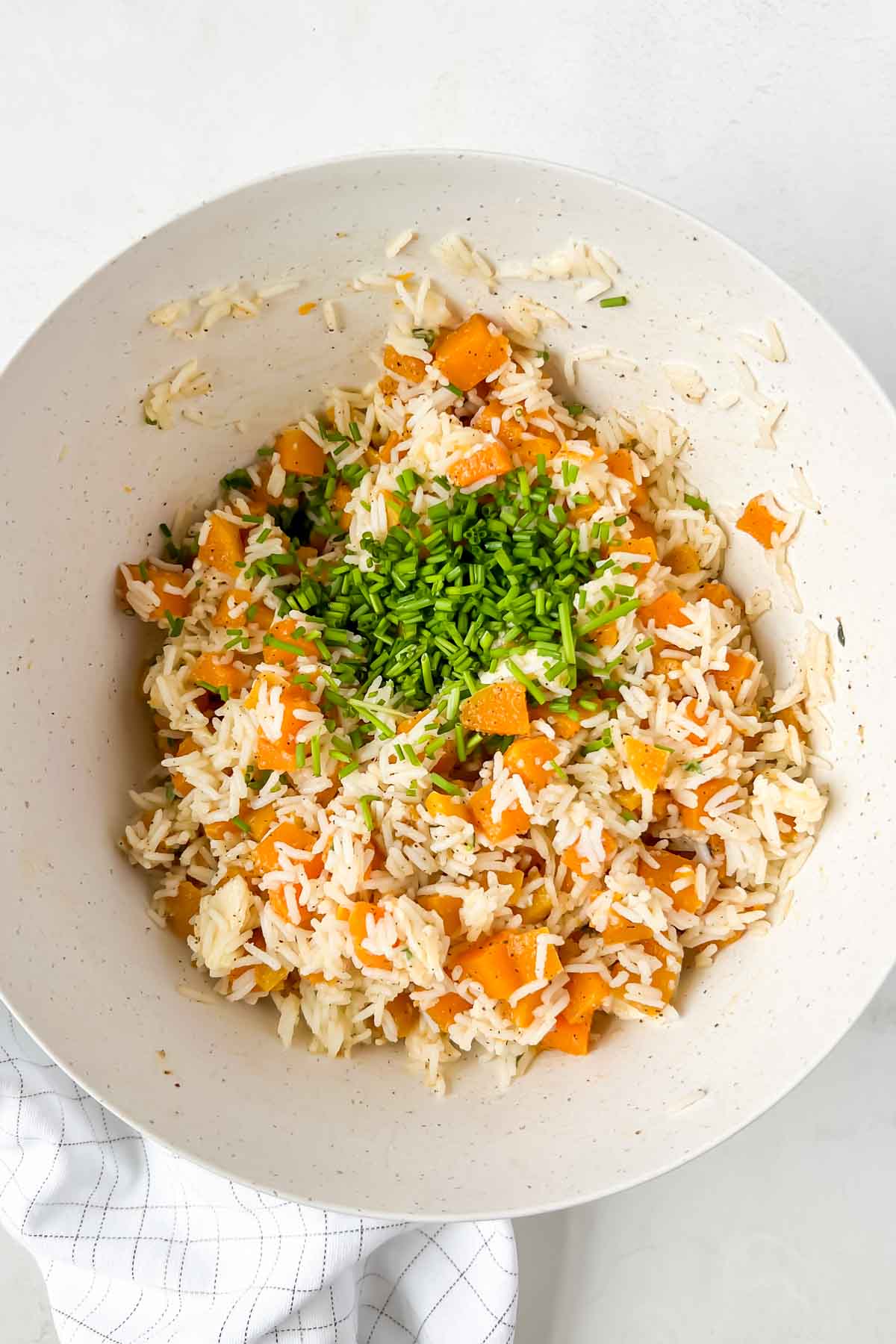basmati rice and seasoned butternut squash and herbs in white mixing bowl.