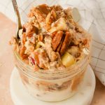 pecan pie overnight oats garnished with toasted pecans in a small glass jar with silver spoon.
