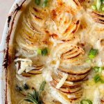 french onion au gratin potatoes garnished with green onions and a rosemary sprig.
