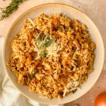 french onion rice with grated cheese and sage leaves on top.