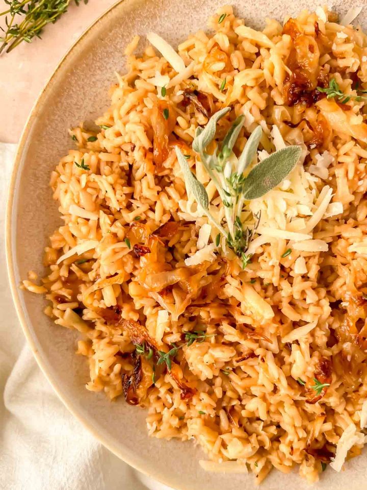 french onion rice with grated cheese and sage leaves on top.