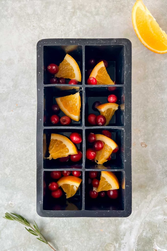 orange, cranberry, and rosemarry in ice cube mold.