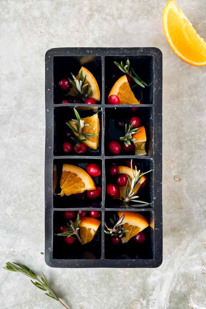 orange, cranberry, and rosemarry in ice cube mold.