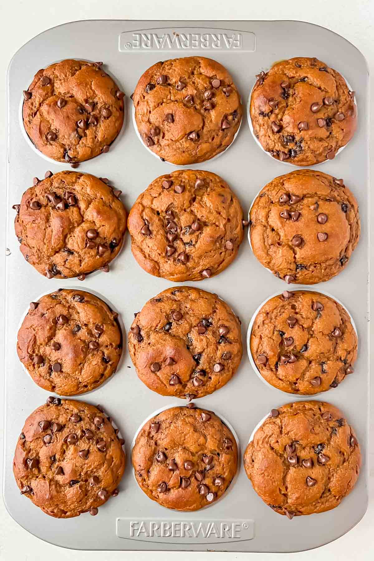 pumpkin protein muffins with chocolate chips in silver muffin tin.