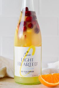light hearted bottle of white wine with sliced citrus fruit and cherries stuffed in the bottle.