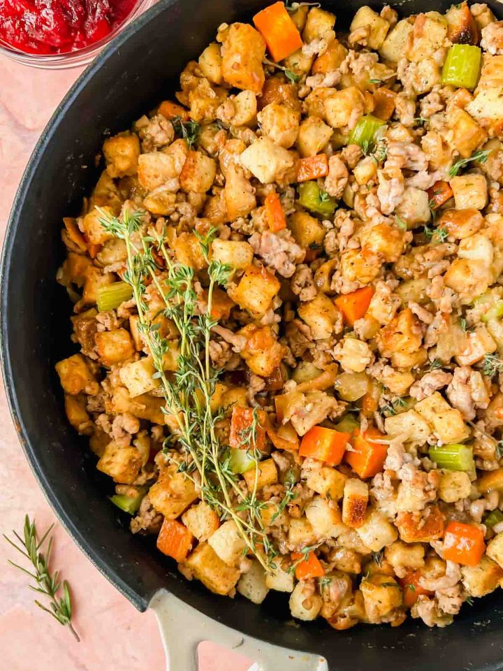 stove top stuffing with sausage with broiled top in tan skillet topped with herbs.