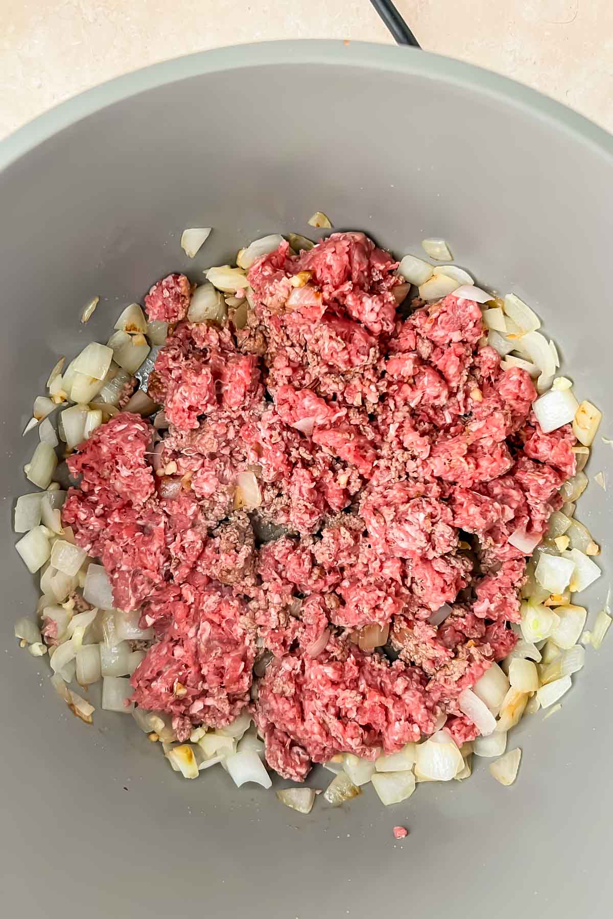 ground meat and onions cooking in gray soup pot.