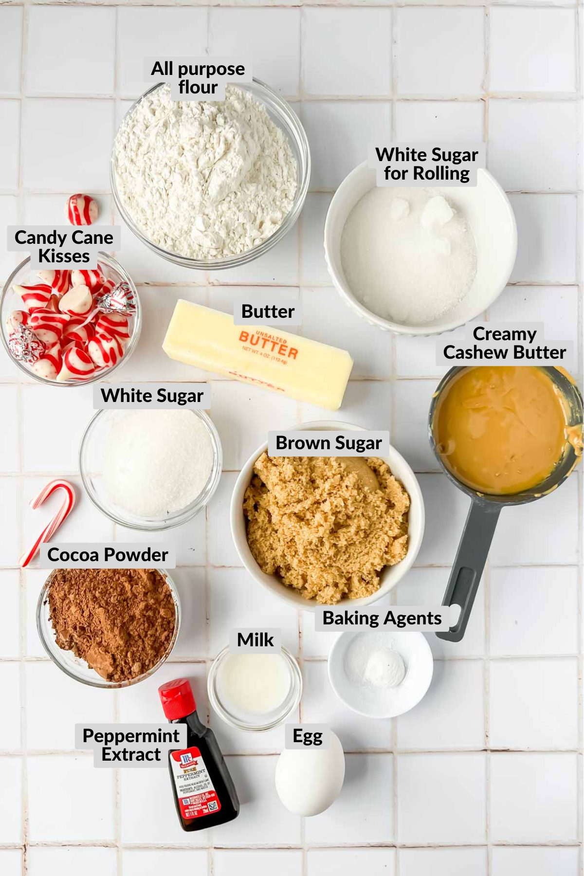ingredients for chocolate peppermint kiss cookies on white tile background.