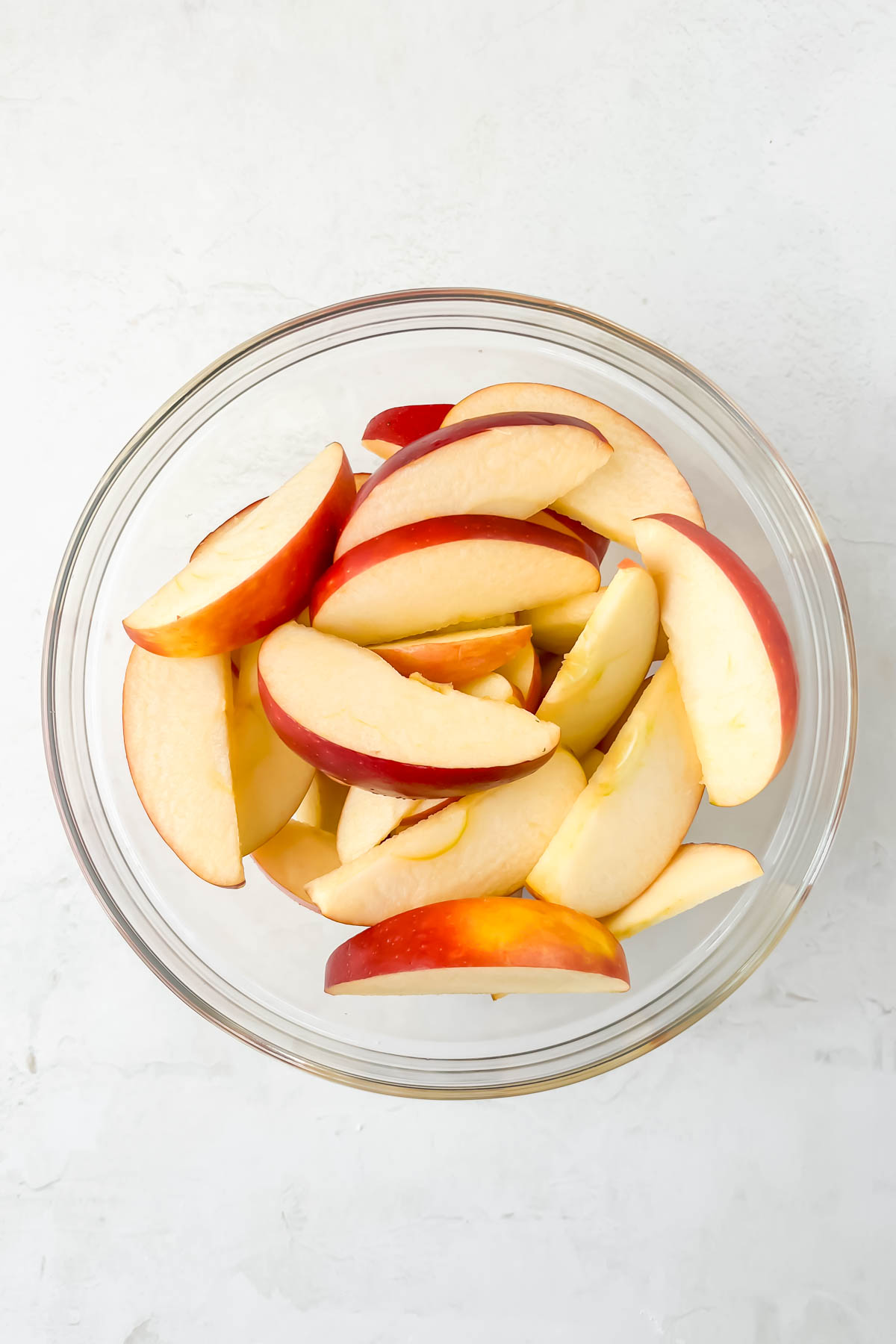 diced apples in a glass bowl on a white background. 