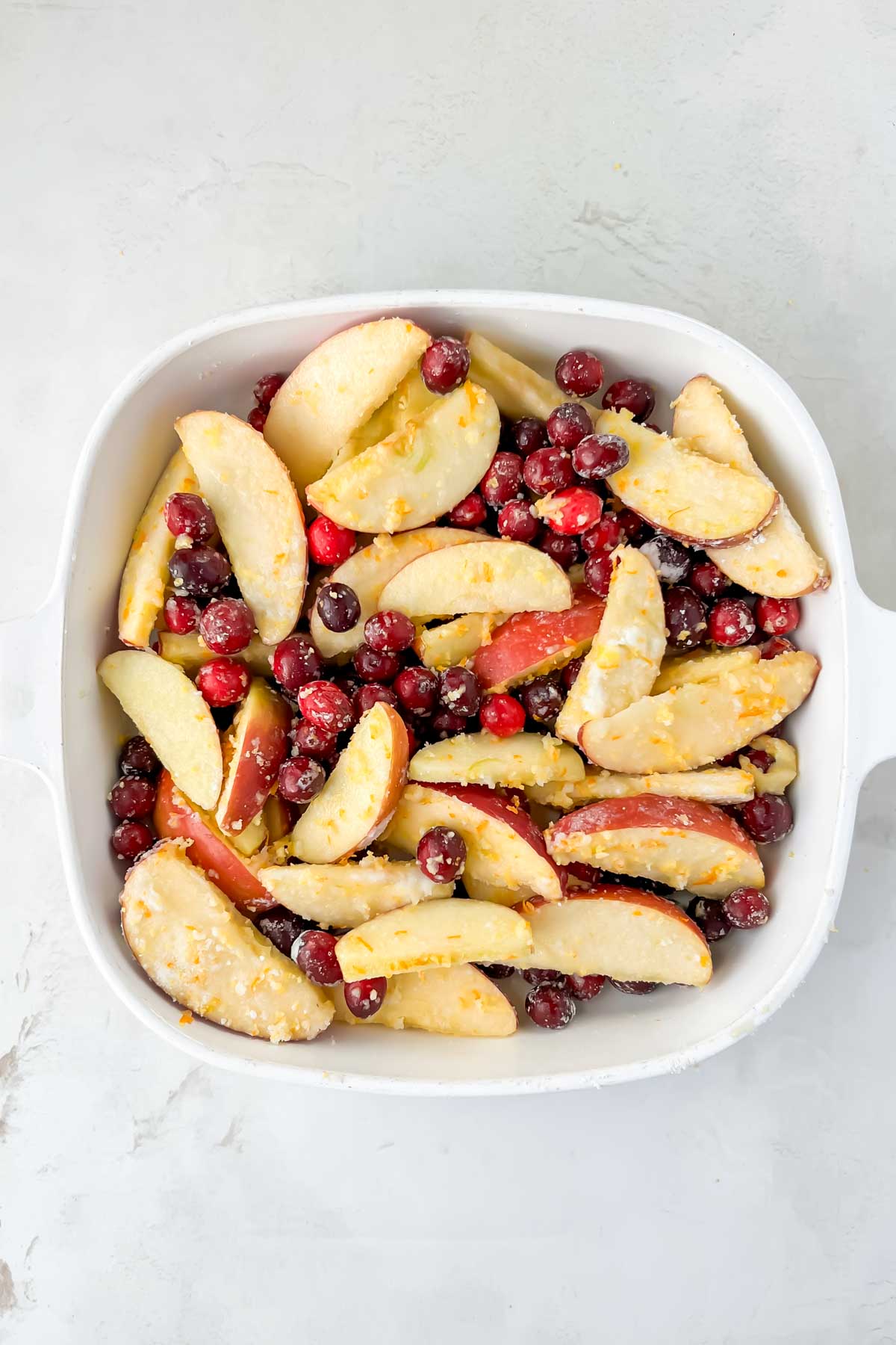 white square casserole dish filled with cranberry and apple mixture. 