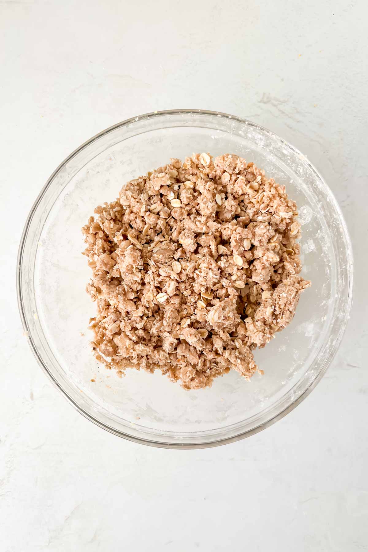 streusel topping mixture folded together in a glass bowl on white background. 