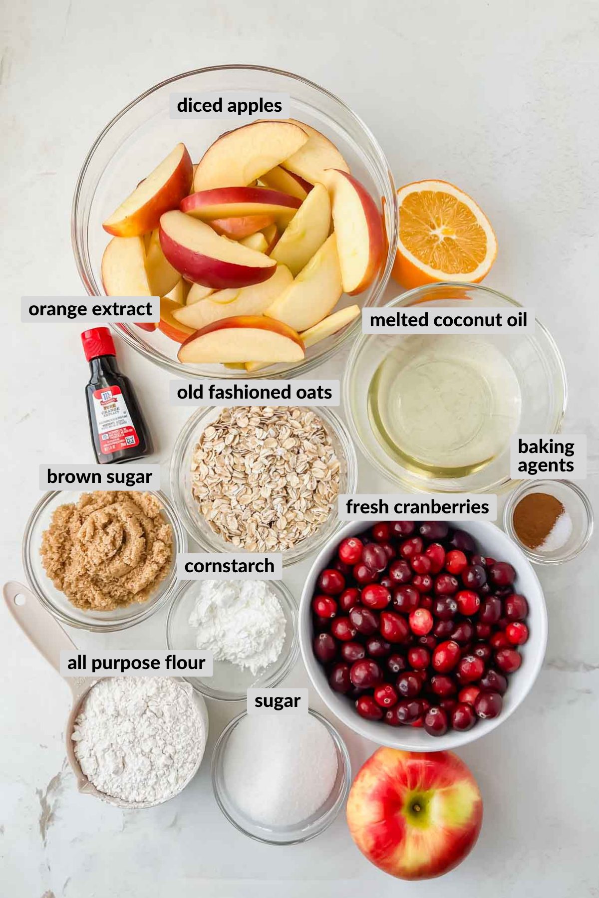 ingredients needed for cranberry apple crisp in individual bowls on white background. 