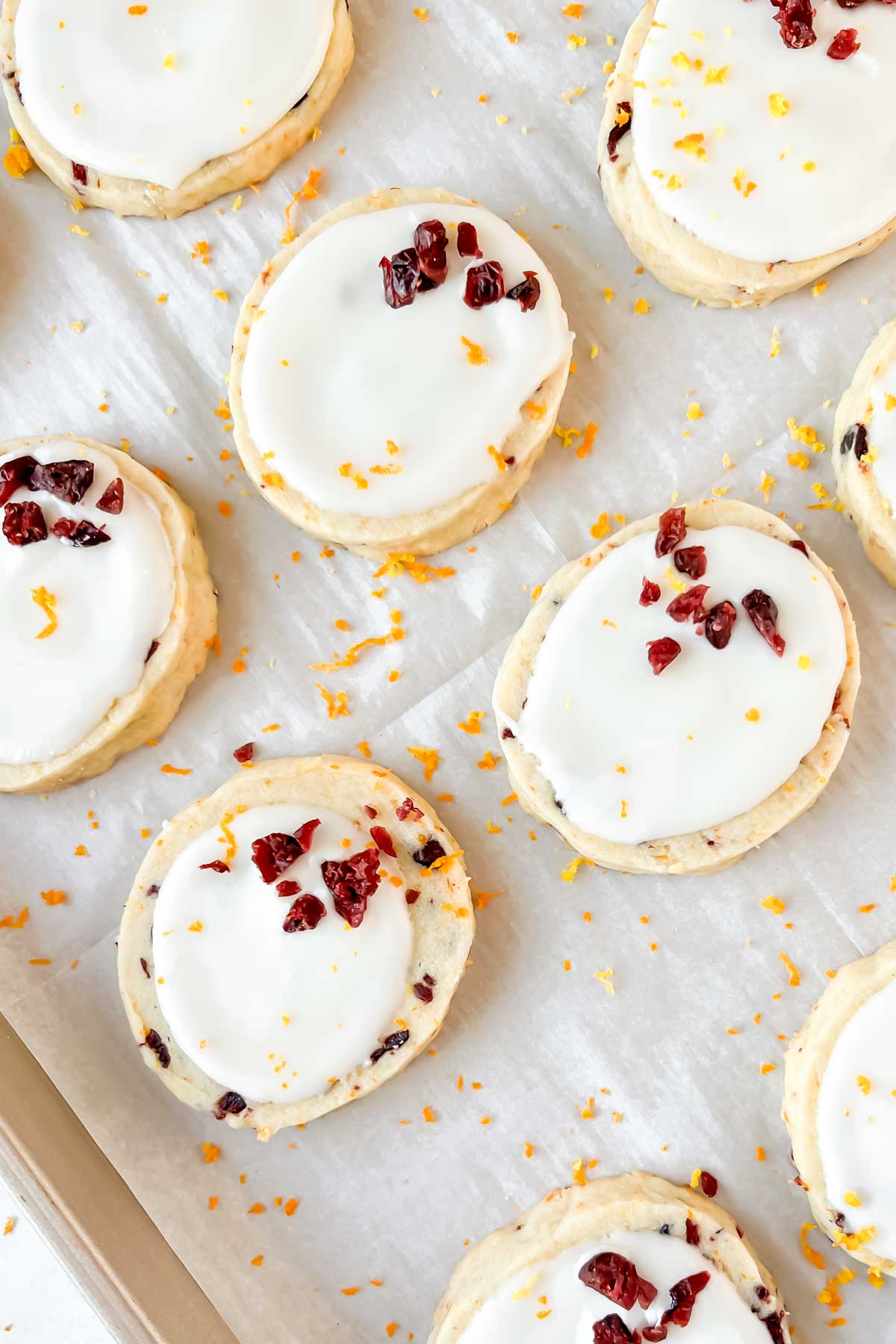 cranberry orange shortbread cookies topped with white glaze and orange zest.