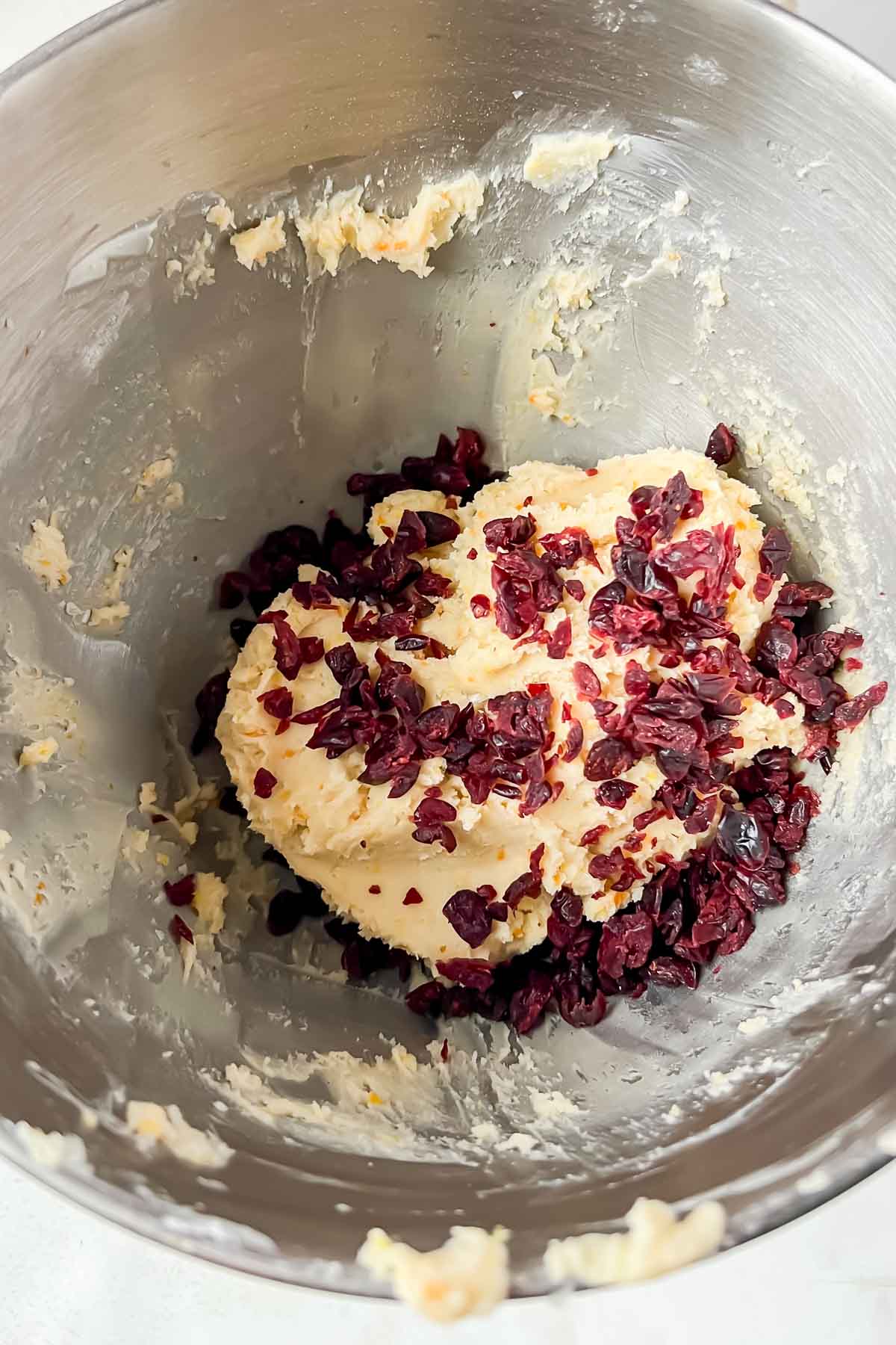 cookie dough in silver bowl with dried cranberries added in bowl.