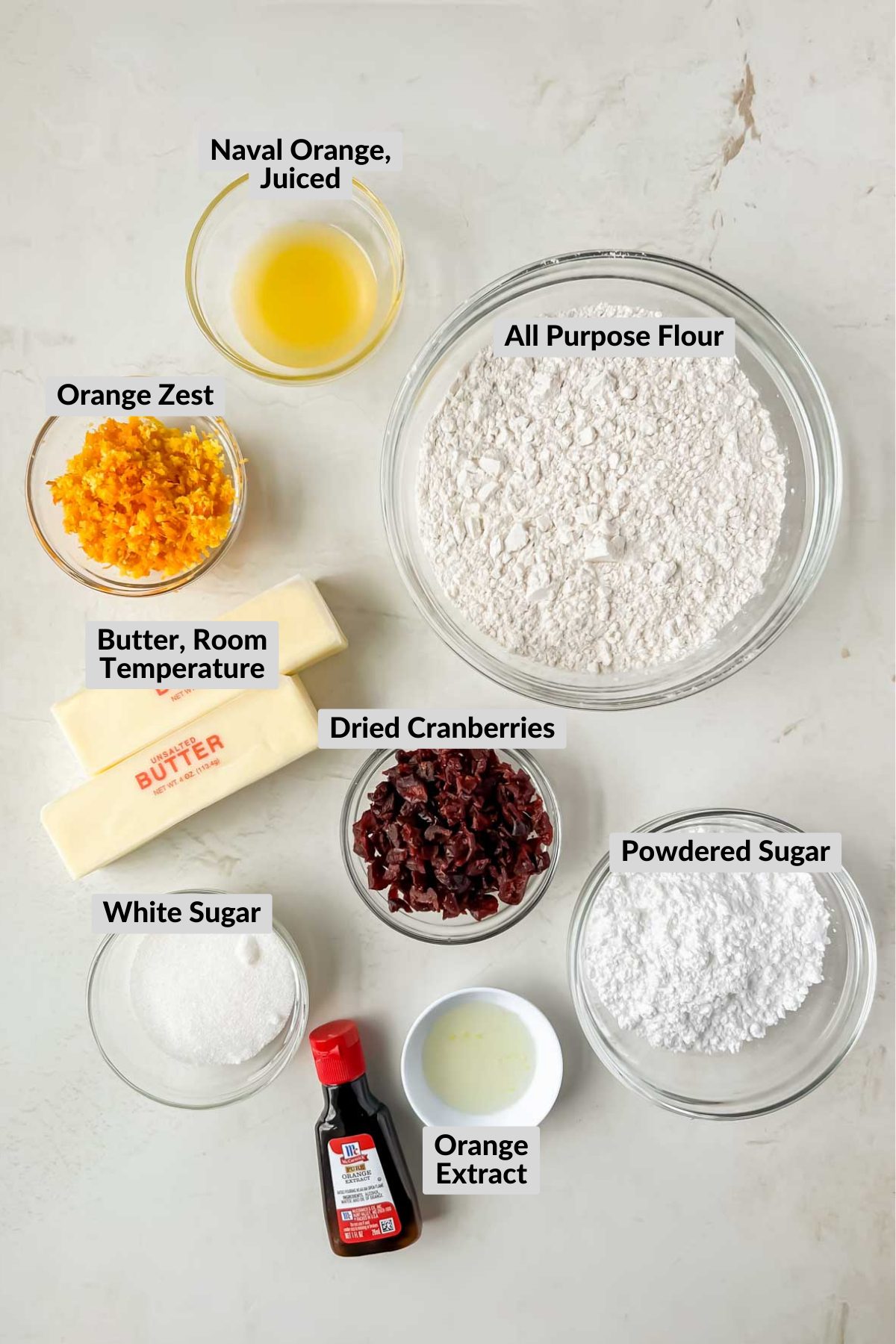 ingredients for cranberry orange shortbread cookies in individual bowls on white background.