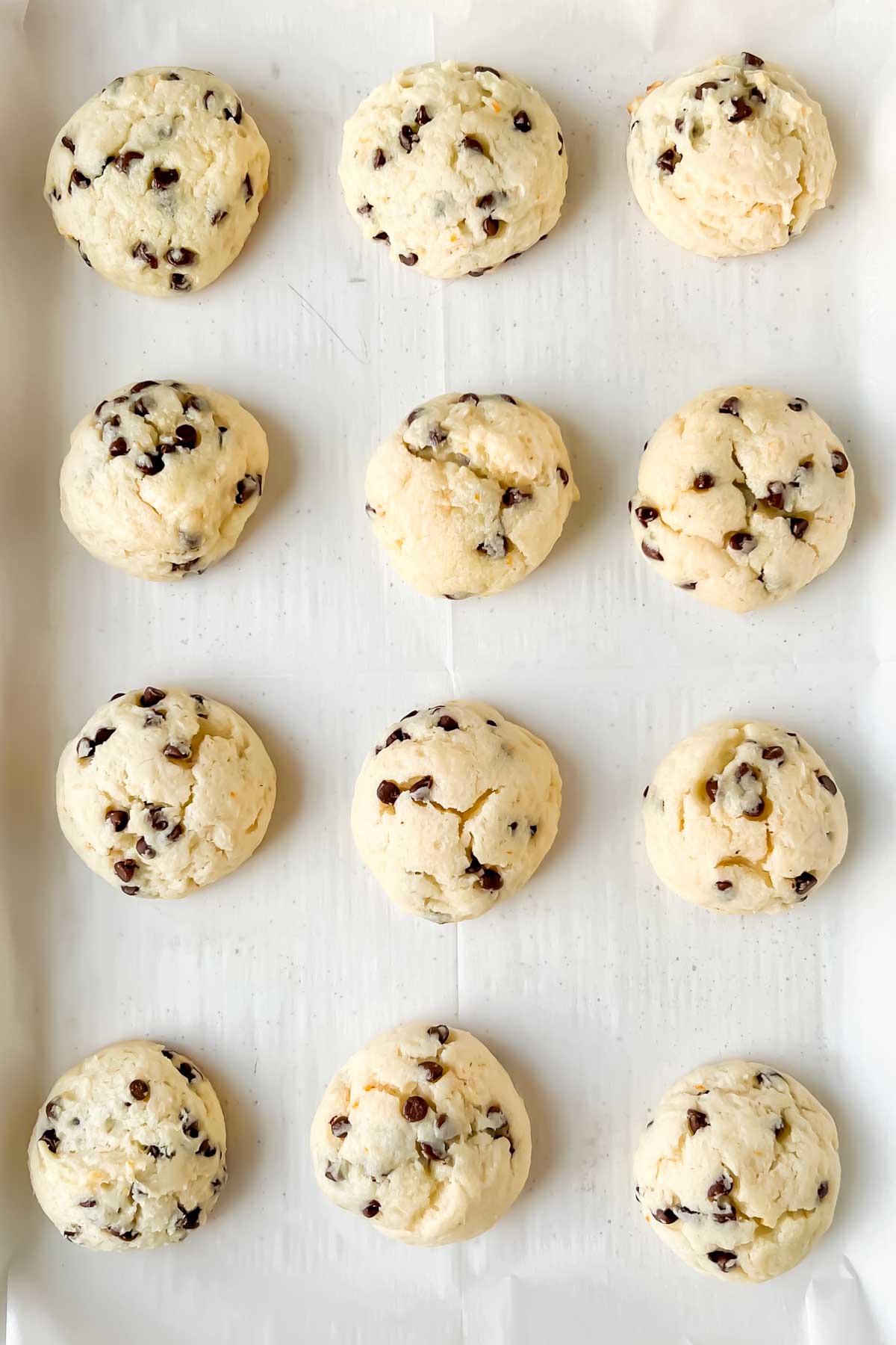 12 ricotta chocolate chip cookie dough balls on parchment lined baking sheet.