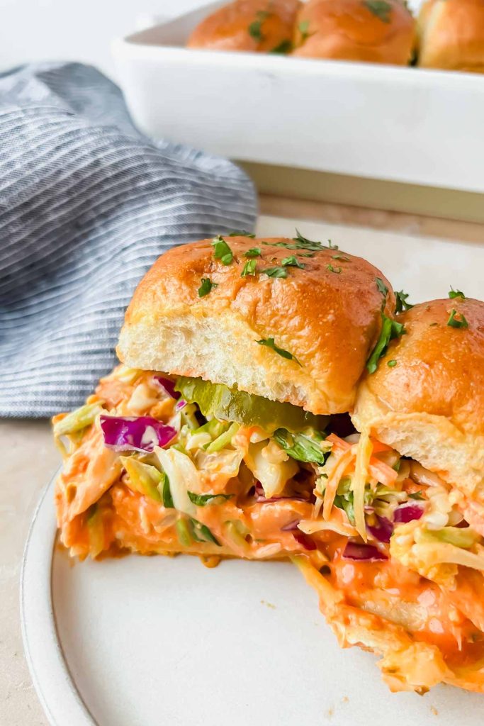two buffalo chicken sliders on white serving plate.