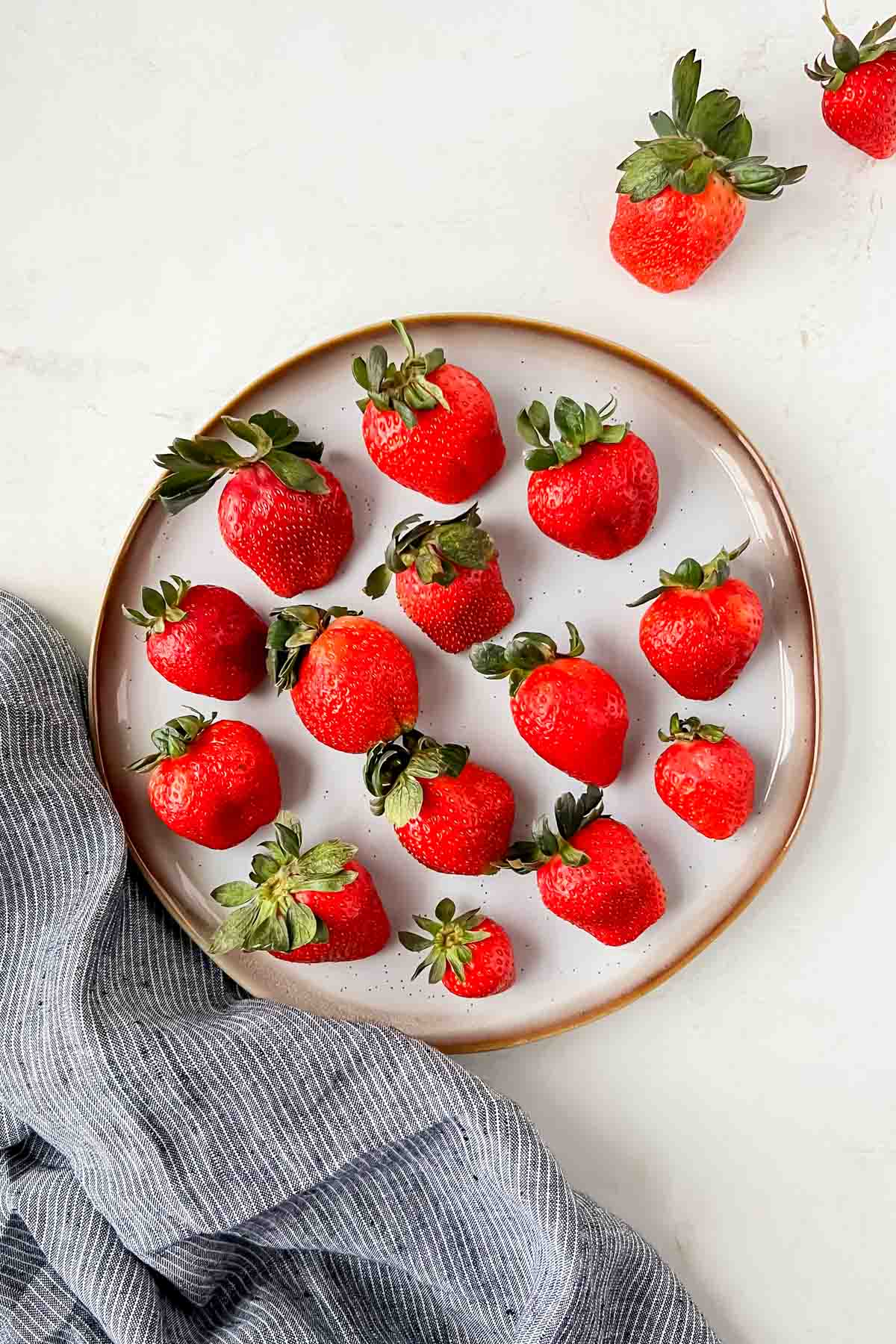 champagne soaked strawberries aligned on white plate.