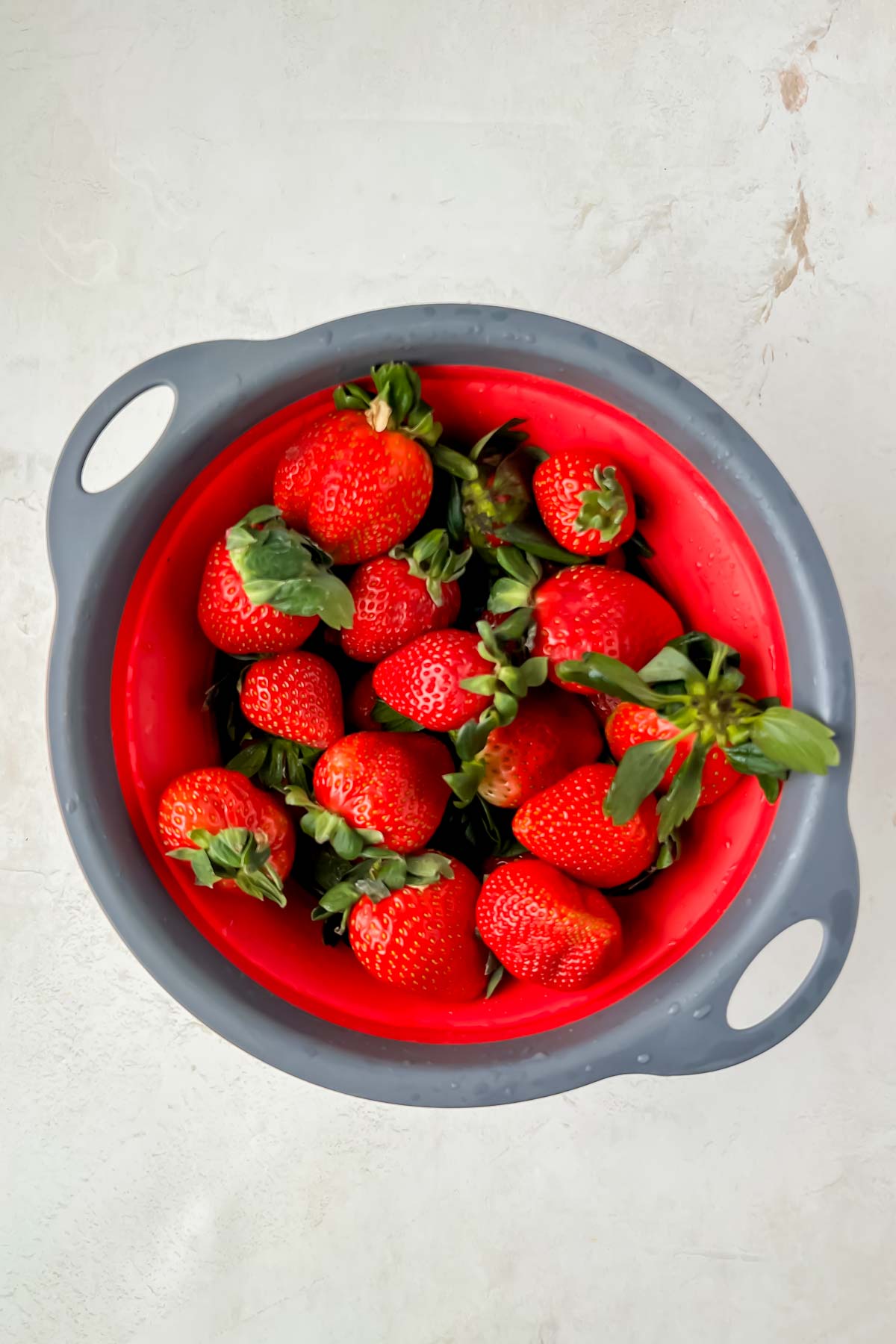 fresh strawberries in red strainer.