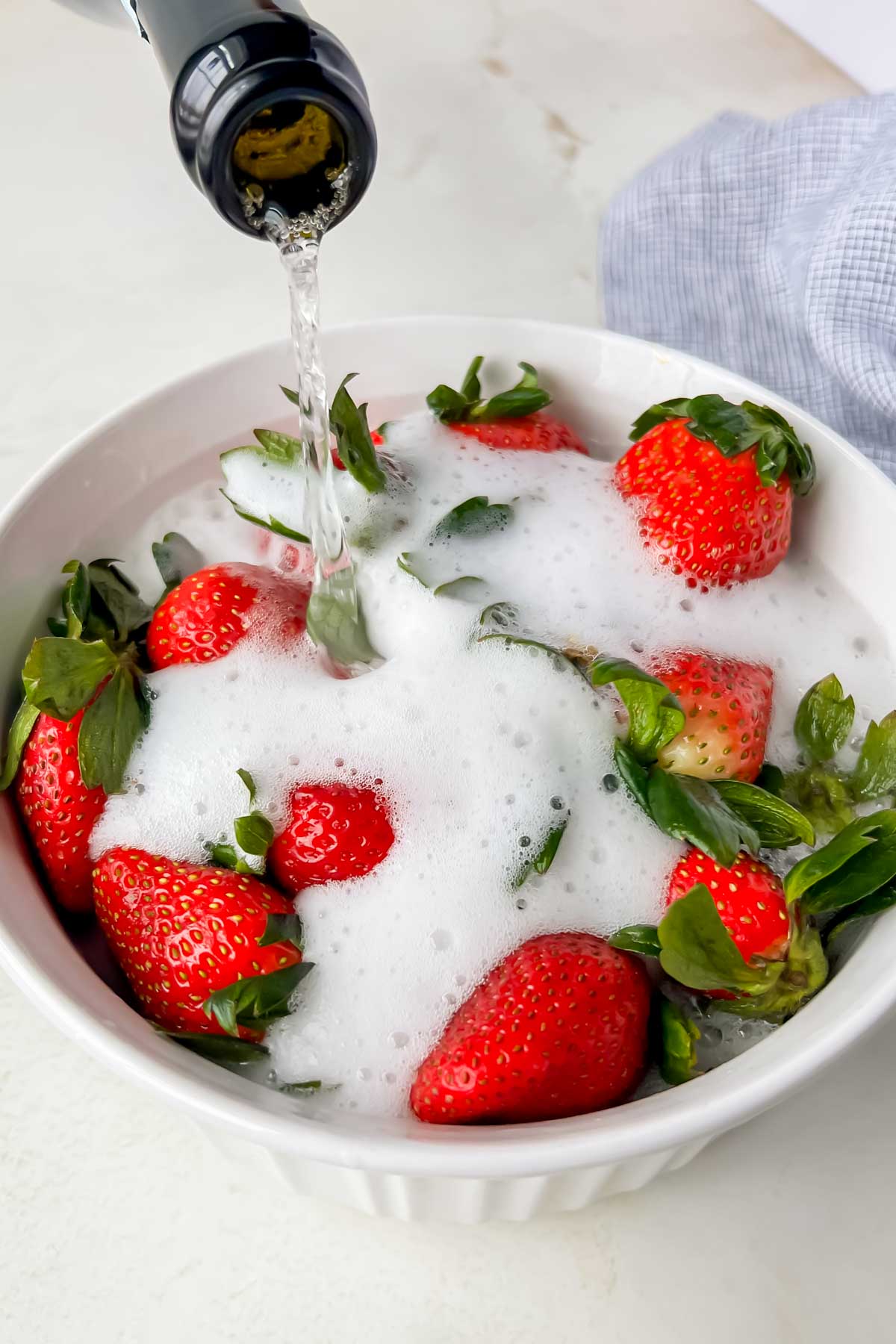 Champagne being poured over fresh strawberries.
