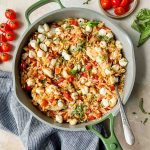 chicken orzo bake in gray skillet topped with fresh herbs.