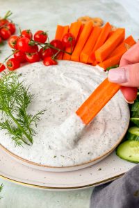 carrot dipping into cottage cheese ranch dip with fresh dill as garnish.