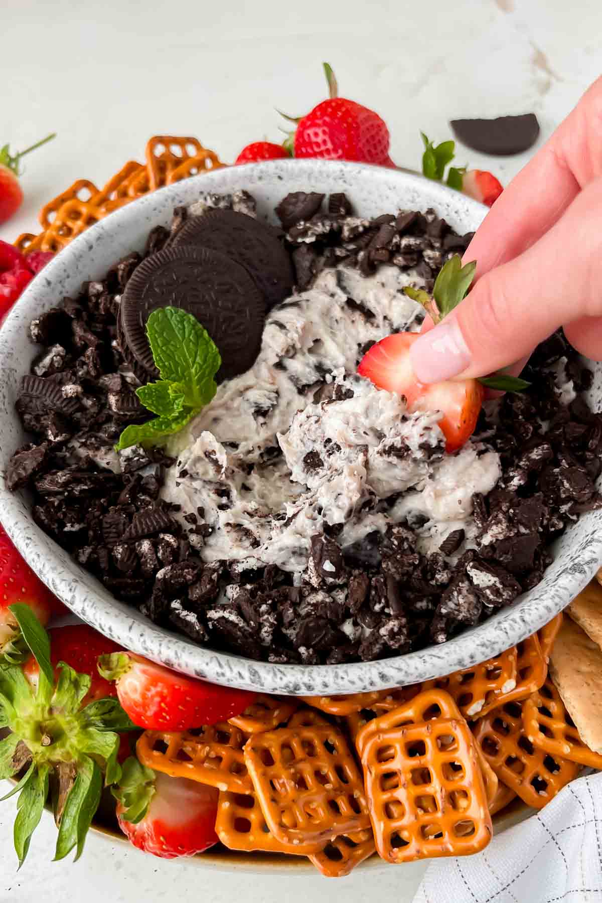 halved strawberry being dipped into oreo dip.