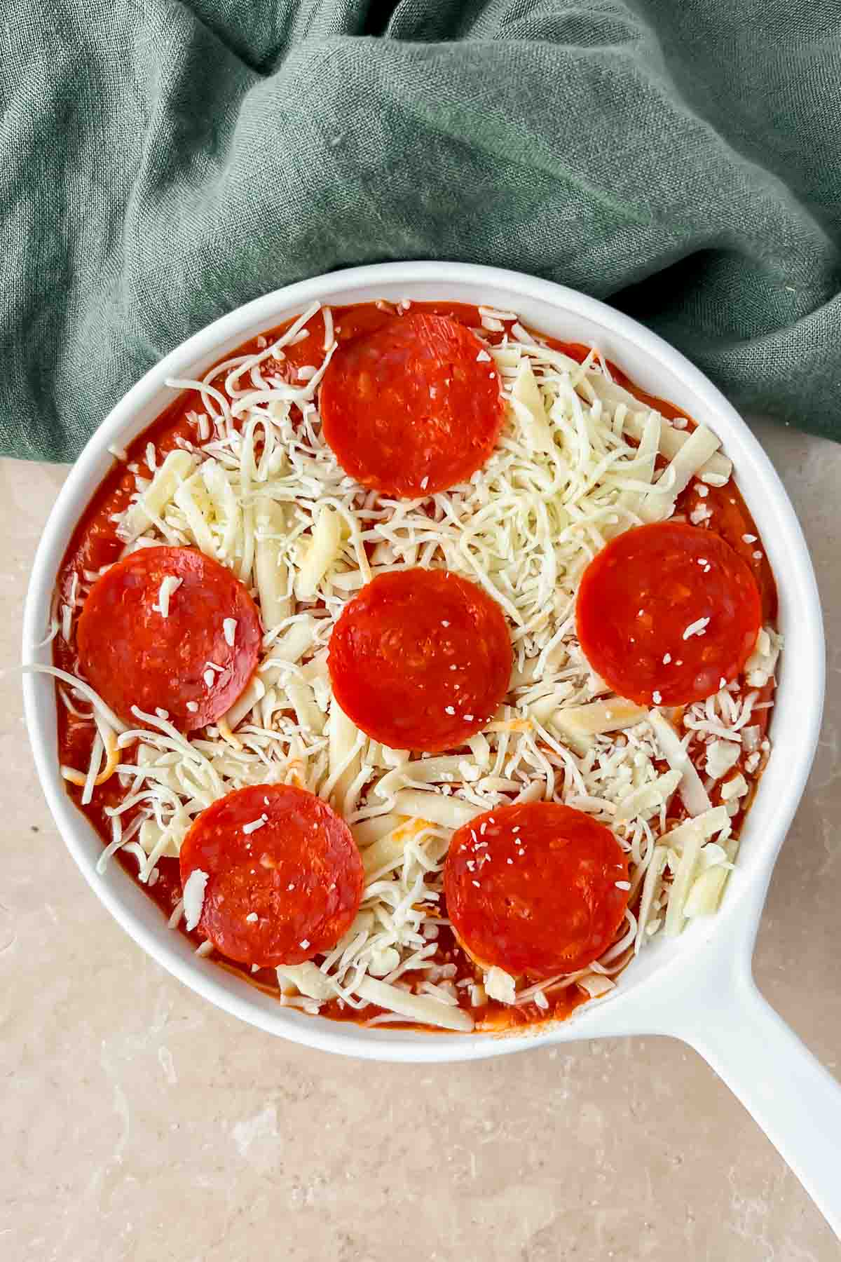 unbaked pepperoni pizza dip in white skillet.