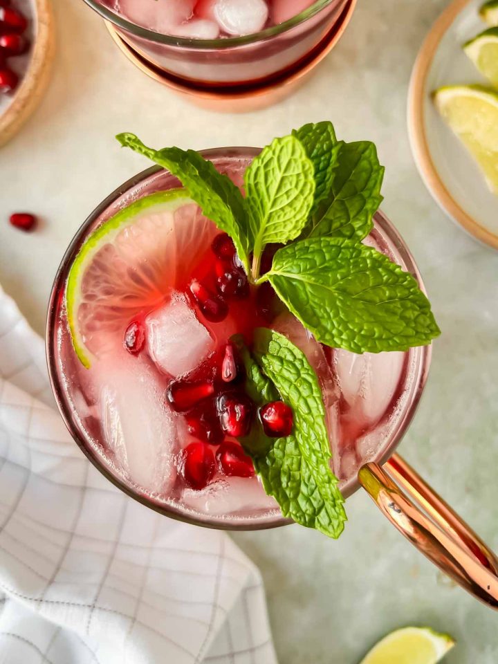 pomegranate moscow mule in copper mug garnished with fresh mint and pomegranate seeds.