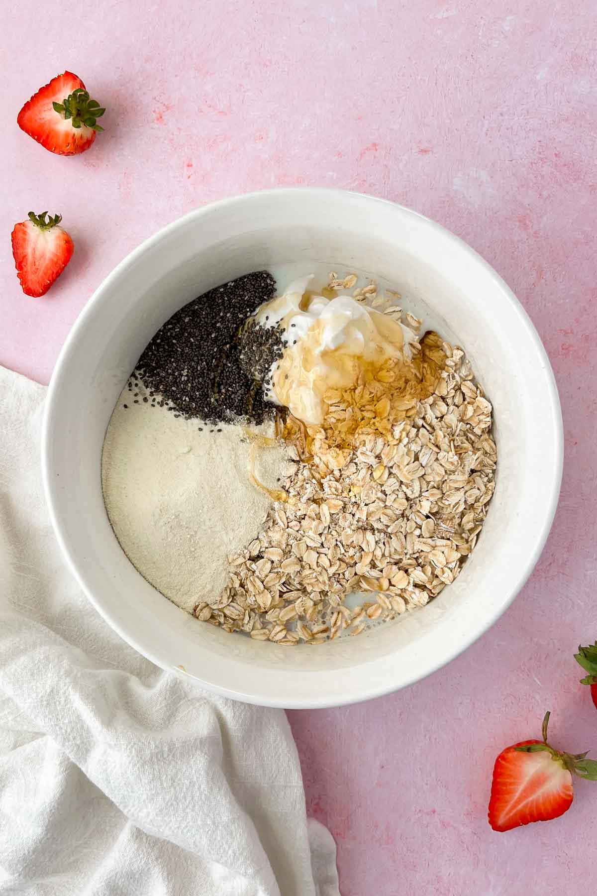 strawberry cheesecake overnight oats ingredients in white mixing bowl.