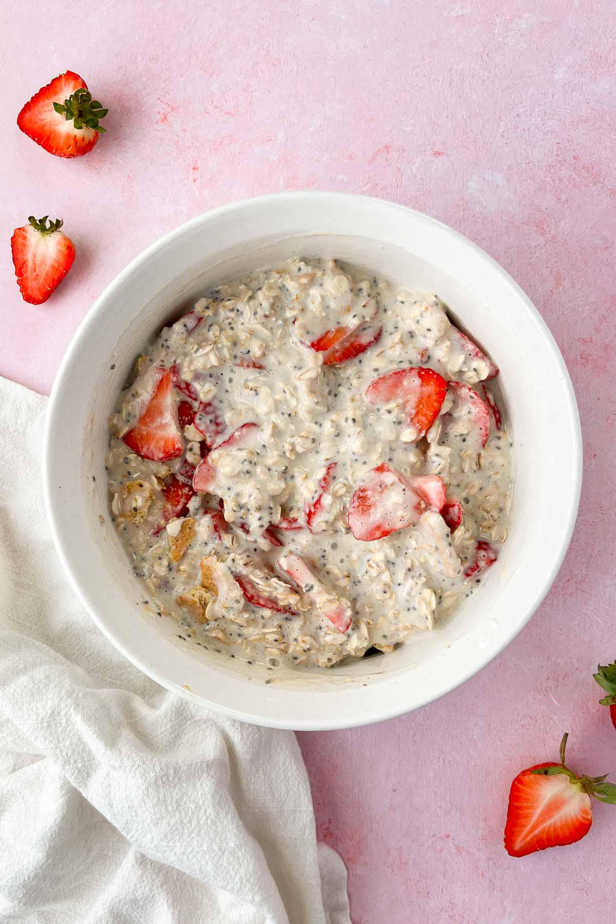 strawberry cheesecake overnight oats ingredients mixed together in white mixing bowl.