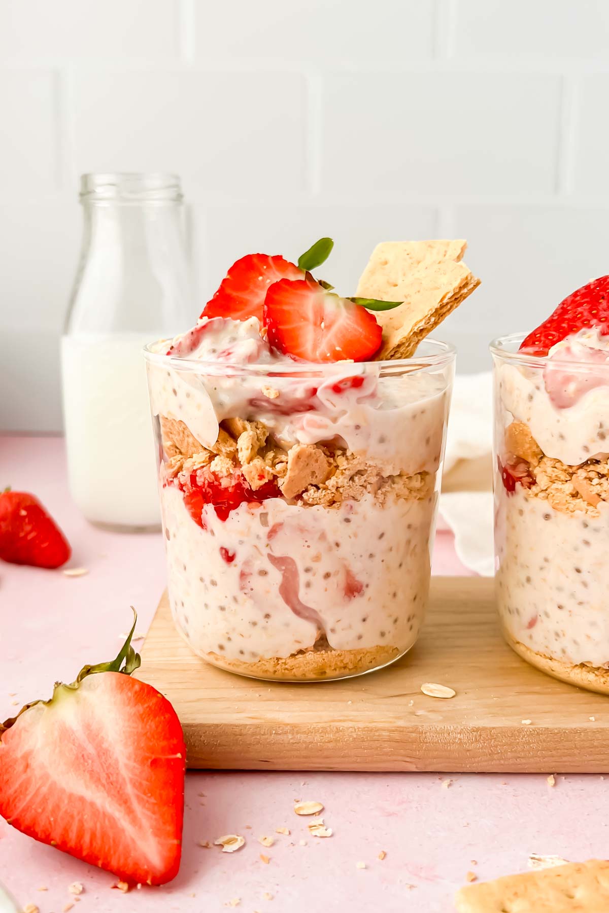 jar of strawberry cheesecake overnight oats garnished with strawberry slices and graham crackers.